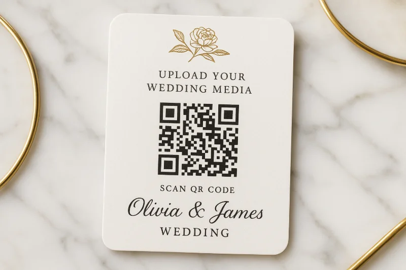 Elegant wedding QR code card with rose gold accents on marble table displaying 'Upload Your Wedding Media' with clear scanning instructions